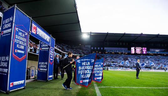 Två pojkar med flaggor gör entre innan fotbollsmatchen i