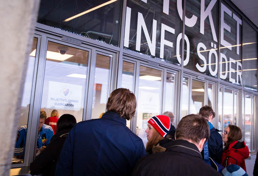 En kvinna med en Norsk mössa står vid biljettluckan.