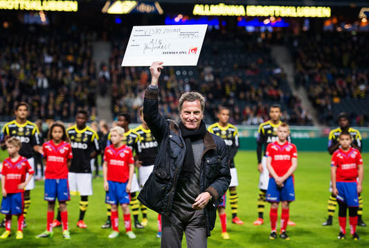 En representant från AIK håller upp en check från