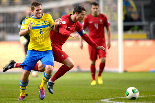 Sveriges Anders Svensson tacklar Portugals Cristiano Ronaldo