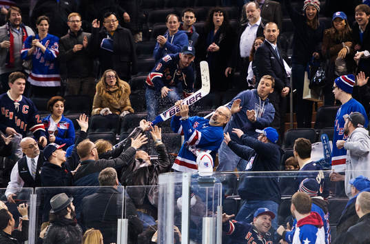En man fångar en hockeyklubba som Henrik Lundqvist kastat