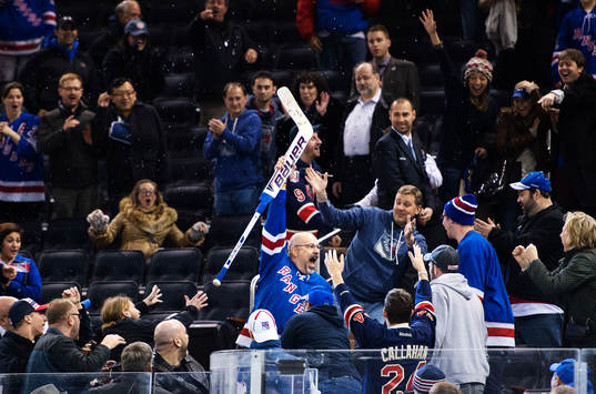En man fångar en hockeyklubba som Henrik Lundqvist kastat