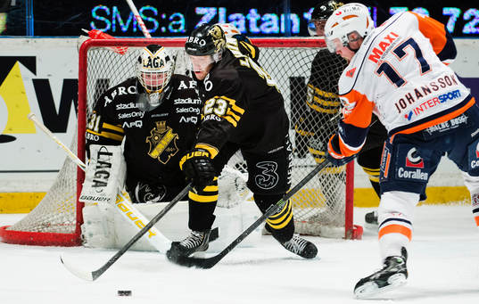 s Jonas Liwing försöker peta undan pucken framför AIK:s