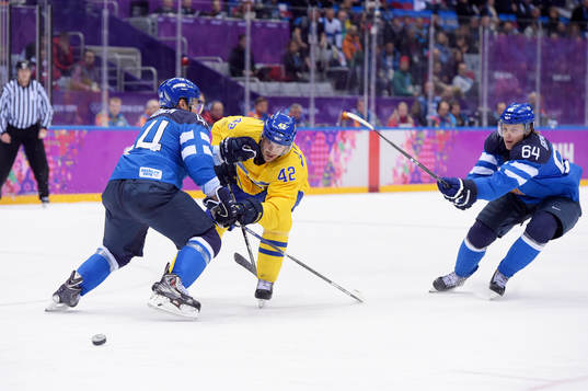 Sveriges Jimmie Ericsson kämpar för pucken med Finlands