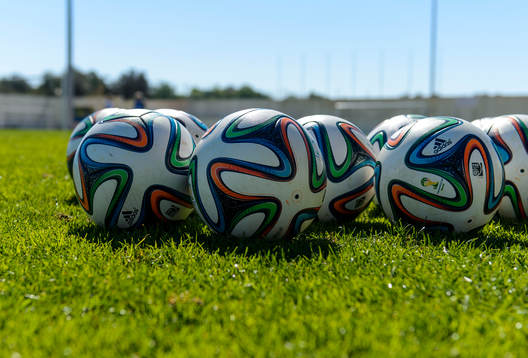 Fotbollar ligger på gräset på en träning