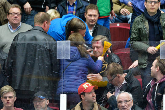 En man i publiken träffas av pucken i huvudet