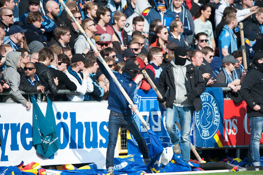 En maskerad Djurgården-supportrar tar flaggstången som
