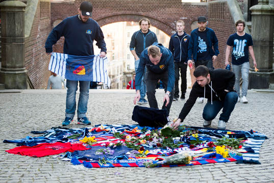 Personer sörjer vid tända ljus och utlagda halsdukar och