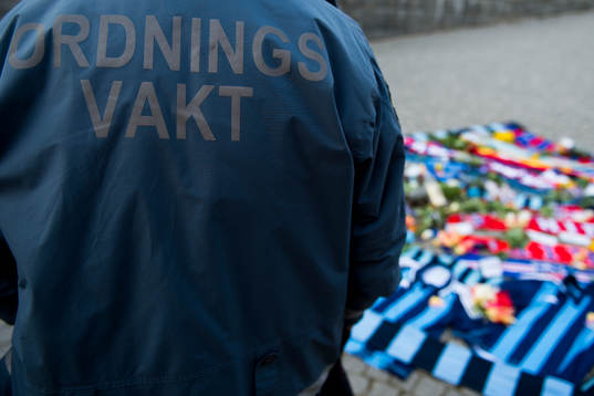 En ordningsvakt vid tända ljus och utlagda halsdukar och