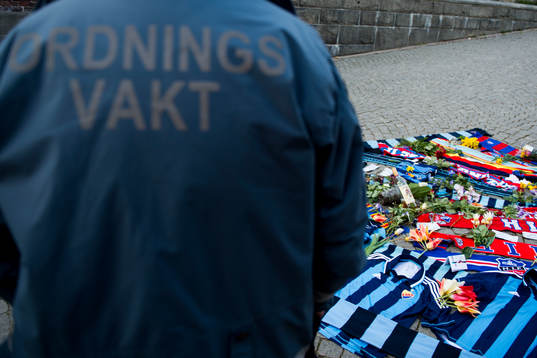 En ordningsvakt vid tända ljus och utlagda halsdukar och