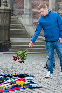 Personer sörjer vid tända ljus och utlagda halsdukar och