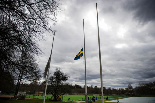 En svensk flagga och en Djurgårdsflagga hänger på halv