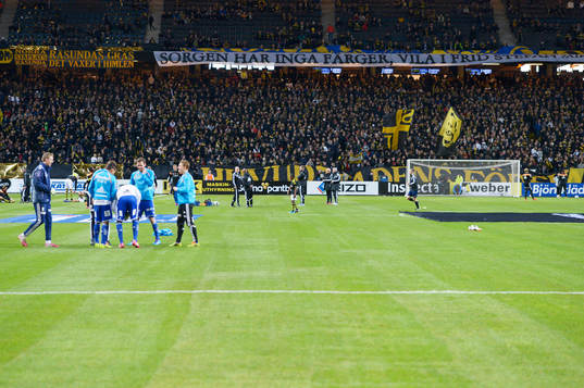 Spelarna värmer upp med banderollen Sorgen har inga