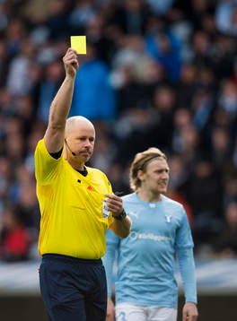 Domare Martin Hansson delar ut ett gult kort