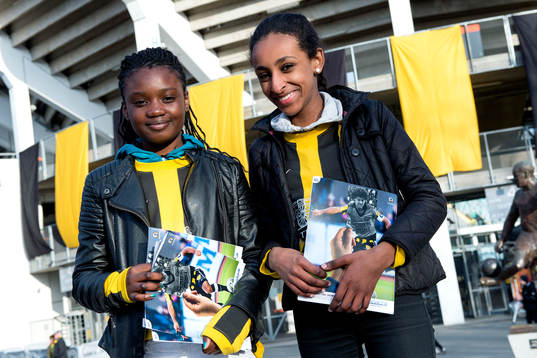 Unga volontärer med matchprogram utanför arenan innan