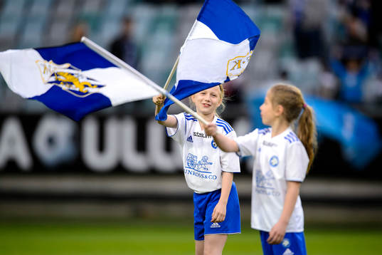 Två tjejer viftar med flaggor innan fotbollsmatchen i