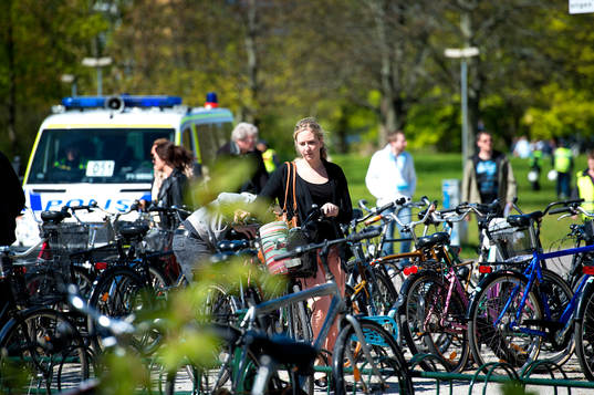 En kvinna parkerar en cykel i ett cykelställ
