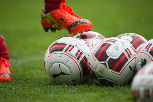 Fotbollssko och bollar i det våta gräset vid Helsingborgs