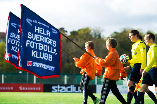 Bollkallar går in på planen bärandes flaggor
