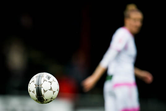 En boll och en oskarp damfotbollsspelare