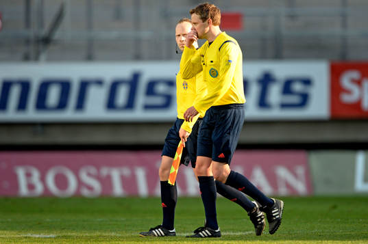 Domare Markus Strömbergsson och en linjedomare lämnar