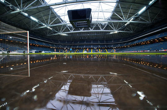 Friends Arena speglas i vatten som regnat in