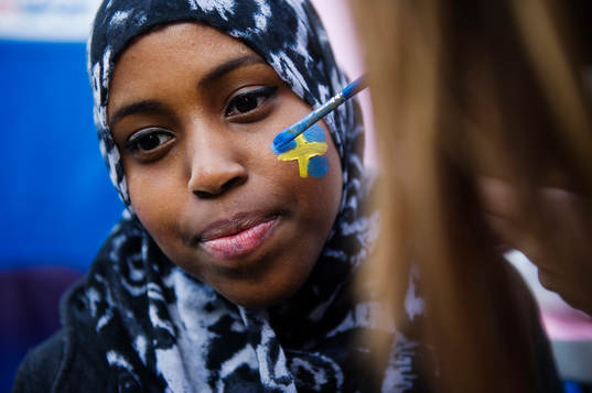 En tjej får en svensk flagga målad i ansiktet