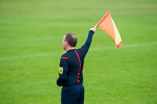 Assisterande domaren vinkar för offside i matchen i DM