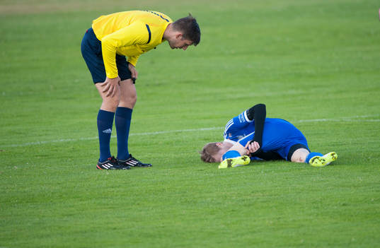 Domaren tittar till en skadad spelare i matchen i division