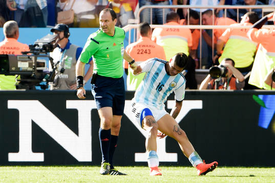 Jonas Eriksson, domare hjälper Argentinas Marcos Rojo upp