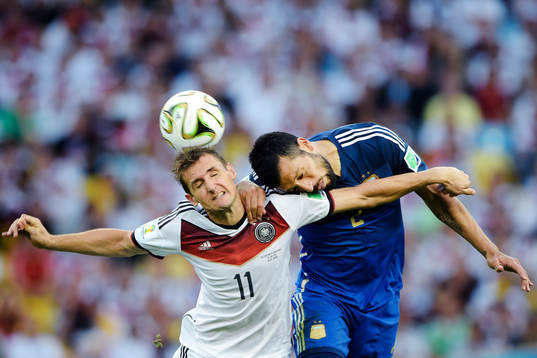 Tysklands Miroslav Klose i en luftduell mot Argentinas