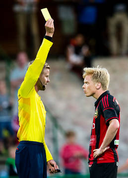 Domare Glenn Nyberg ger ett gult kort till Brommapojkarnas