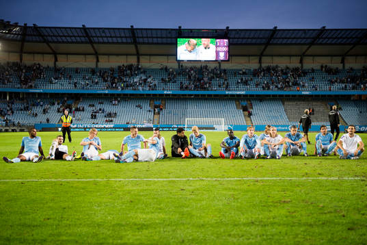 Malmö FFs spelare sitter på planen och lyssnar på