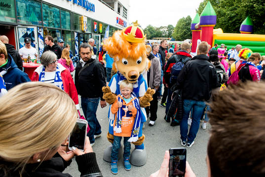 Maskoten Leo med en ung supporter innan fotbollsmatchen i