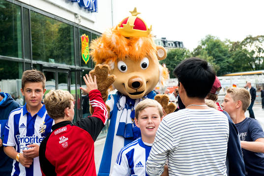 Unga supportrar med maskoten Leo innan fotbollsmatchen i
