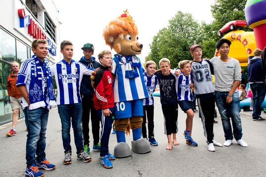 Unga supportrar med maskoten Leo innan fotbollsmatchen i