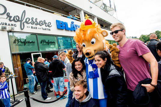 Maskoten Leo med supportrar innan fotbollsmatchen i