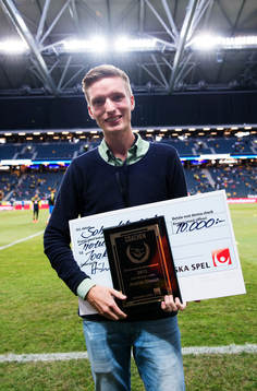 Joakim Olsson poserar med ett diplom och check från