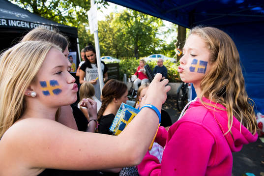 Tjejer med svenska flaggan målad på kinden innan