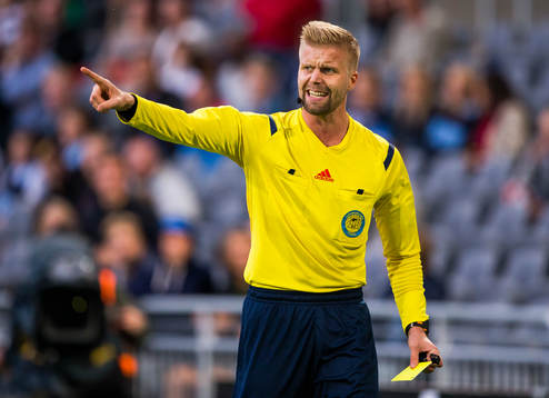 Domare Glenn Nyberg håller i ett gult kort