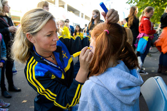 En tjej får ansiktet målat innan fotbollsmatchen i