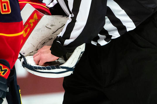 En domare plockar pucken ur målvaktens plockhandske