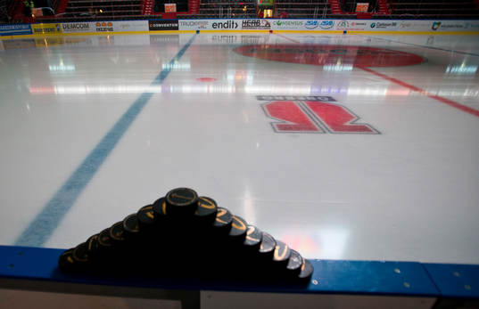 Hockeypuckar uppstaplade på sargen i Behrn Arena innan