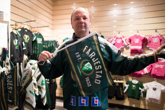 En Färjestadssupporter visar upp flaggor i butiken