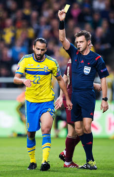Sveriges Erkan Zengin får ett gult kort av domare Nicola