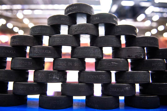 Puckar uppstaplade på sargen till uppvärmningen