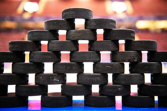 Puckar uppstaplade på sargen till uppvärmningen