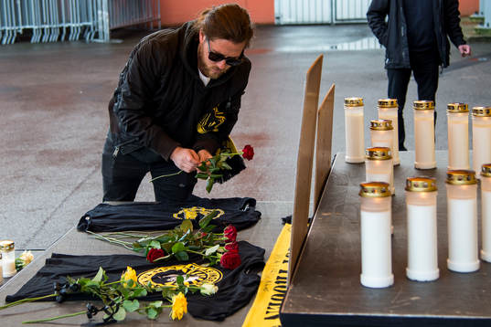 Supporter lägger ner en röd ros och tröja från