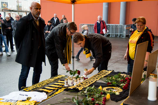 Sörjande tänder ljus och lägger ner blommor