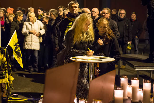 Sörjande skriver i kondoleansboken vid minnesplatsen